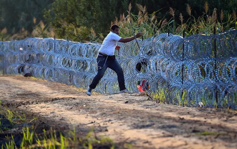 A migrant tries to pass a barbed fence at the Hungarian-Serbian border near Roszke, on August 27, 2015. As Europe struggles with its worst migrant crisis since World War II, Hungary has become, like Italy and Greece, a "frontline" state. So far this year, police say around 141,500 migrants have been intercepted crossing into Hungary, mostly from neighbouring Serbia.  AFP PHOTO / ATTILA KISBENEDEK