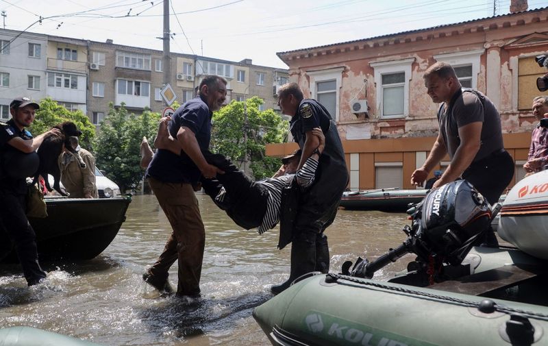 Ukrainian security forces carry an elderly resident to a boat during an evacuation from a flooded area in Kherson on June 7, 2023, following damages sustained at Kakhovka hydroelectric power plant dam. Ukraine was evacuating thousands of people on June 7 after an attack on a major Russian-held dam on June 6, 2023, unleashed a torrent of water, inundating two dozen villages and sparking fears of a humanitarian disaster. (Photo by Oleksandr GIMANOV / AFP)