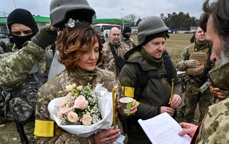 Servicemen of Ukrainian territorial defence, Valery (3rdR) and Lesya (2ndL), get married not far from check-point on Kyiv outskirts on March 6, 2022. (Photo by Genya SAVILOV / AFP)