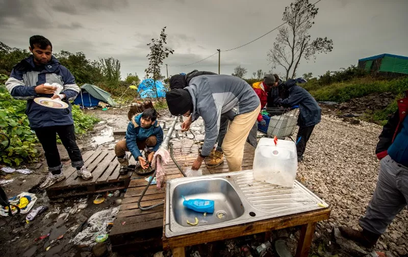 (FILES) A picture taken on October 21, 2015 shows migrants having a wash at the "New Jungle" migrant camp in Calais, where thousands of migrants live in the hope of crossing the Channel to Britain. A French court on November 2, 2015 ordered the state to improve conditions at the giant "New Jungle" migrant camp in Calais after NGOs called for immediate action over "serious human rights violations". AFP PHOTO / PHILIPPE HUGUEN
