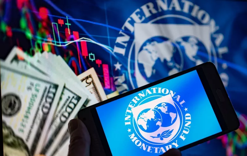 IMF International Monetary Found logo seen on Mobile with IMF with Dollar bils on screen in this foto illustration. On 3 January 2023, in Brussels - Belgium. (Photo illustration by Jonathan Raa/NurPhoto) (Photo by Jonathan Raa / NurPhoto / NurPhoto via AFP)