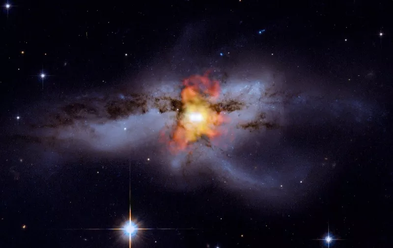 This NASA handout image obtained October 7, 2009 shows an image of NGC 6240 which contains new X-ray data from Chandra (shown in red, orange, and yellow) that has been combined with an optical image from the Hubble Space Telescope originally released in 2008. In 2002, Chandra data led to the discovery of two merging black holes, which are a mere 3,000 light years apart. They are seen as the bright point-like sources in the middle of the image. Scientists think these black holes are in such close proximity because they are in the midst of spiraling toward each other -- a process that began about 30 million years ago. It is estimated that they holes will eventually drift together and merge into a larger black hole some tens or hundreds of millions of years from now. AFP PHOTO/X-ray: NASA/CXC/MIT/C.Canizares, M.Nowak; Optical: NASA/STScI/RESTRICTED TO EDITORIAL USE (Photo by NASA / AFP)