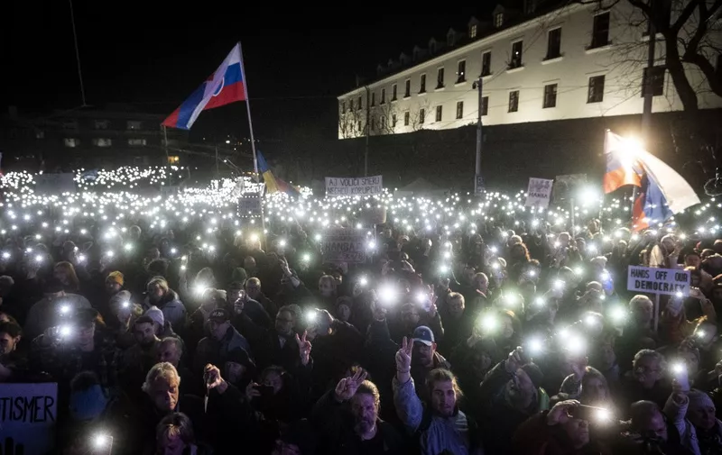 People show the flashlights of their mobile phones as they take part in a demonstration to protest criminal code reforms on course to be passed despite sharp criticism from notably the EU, in front of the Slovak parliament in Bratislava, Slovakia, on Fabruary 7, 2024. The changes, which prompted a wave of anti-government protests, include easing the penalties for corruption and economic offences in the EU and NATO country of 5.4 million. The parliament is expected to pass the controversial reforms via a fast-tracked legislative procedure on February 8, a step that has drawn condemnation from the president and the opposition lawmakers. (Photo by VLADIMIR SIMICEK / AFP)