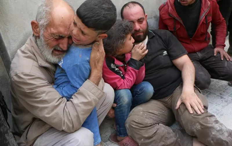 Grief-stricken Syrians sit on the pavement near a building that was targeted in a reported barrel bomb attack by Syrian government forces on the central al-Fardous rebel held neighbourhood of the northern Syrian city of Aleppo, on April 29, 2015, which left a number of people dead, according to locals.   AFP PHOTO / AMC / ZEIN AL-RIFAI
