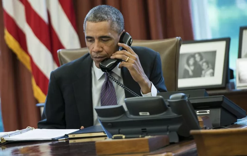 US President Barack Obama speaks on the phone in the Oval Office of the White House October 8, 2014 in Washington, DC. Obama participated in a conference call to discuss the US response to the current Ebola outbreak. AFP PHOTO/Brendan SMIALOWSKI