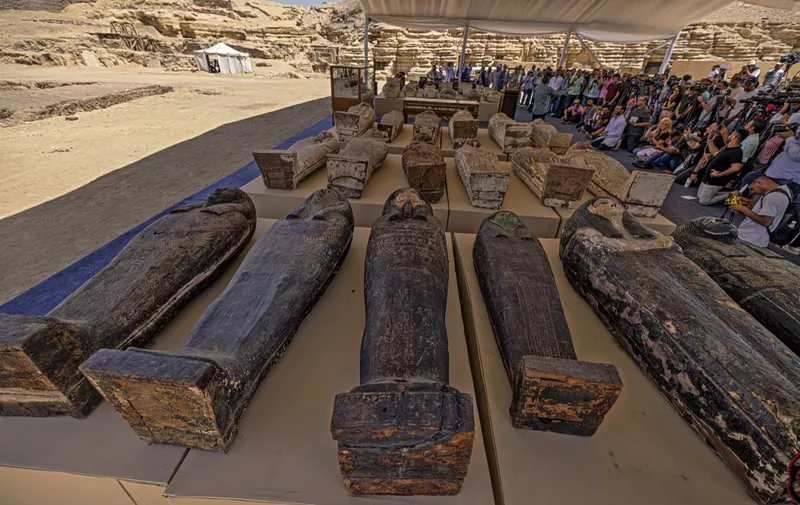 Sarcophaguses found in a cache dating to the Egyptian Late Period (around the fifth century BC) are displayed after their discovery by a mission headed by Egypt's Supreme Council of Antiquities, at the Bubastian cemetery at the Saqqara necropolis, southwest of Egypt's capital on May 30, 2022. - Egypt on May 30 unveiled a cache of 150 bronze statues depicting various gods and goddesses including "Bastet, Anubis, Osiris, Amunmeen, Isis, Nefertum and Hathor," along with 250 sarcophagi at the Saqqara archaeological site south of Cairo, the latest in a series of discoveries in the area. (Photo by Khaled DESOUKI / AFP)