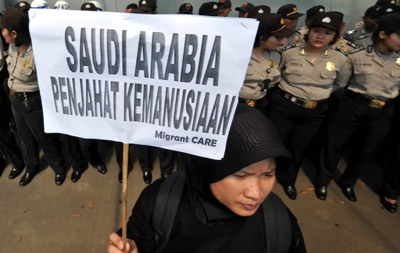 An activist holds a banner reading "Saudi Arabia, is a criminal of humanity" during a protest against the execution of Indonesian migrant worker Ruyati outside the Saudi Arabian embassy in Jakarta on June 21, 2011.  Indonesian lawmakers urged the government to stop sending workers to Saudi Arabia after the beheading of its domestic helper convicted of murdering her Saudi employer. AFP PHOTO / ADEK BERRY / AFP / ADEK BERRY