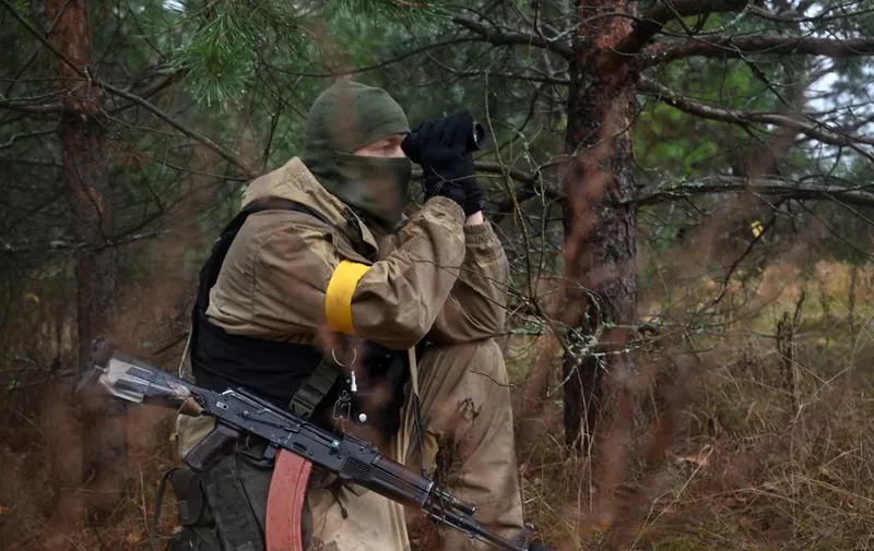 This photograph taken on November 3, 2022 shows a Ukrainian border guard scouting with a monocular near the Ukrainian border with Russia and with Belarus. - The Ukrainian army expressed its alarm to the "growing threat" of a new Russian offensive from its northern neighbor and Moscow ally as Belarus announced the creation of a new joint force with Russia, with up to 9,000 Russian troops and about 170 tanks, to be deployed on its territory. (Photo by Sergei SUPINSKY / AFP)