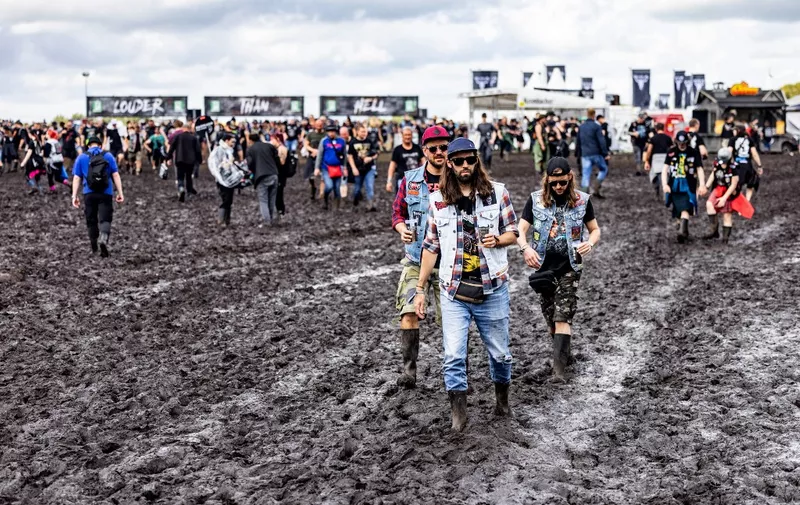 Festival-goers make their way through mud on the grounds of the Wacken Open Air music festival in Wacken, northern Germany on August 3, 2023. The heavy metal music featival was forced to cap attendance after heavy rains turned its farmland venue into a muddy quagmire. Wacken Open Air, one of the largest heavy metal festivals in the world, is scheduled to take place from August 2 until August 5, 2023. (Photo by Axel Heimken / AFP)