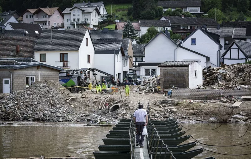A man walks across a temporary bridge in the wine village of Rech near Dernau on the river Ahr, western Germany, on July 30, 2021, weeks after heavy rain and floods caused major damage in the Ahr region. - At least 180 people died when severe floods pummelled western Germany over two days in mid-July, raising questions about whether enough was done to warn residents ahead of time. People are still missing after torrents of water ripped through entire towns and villages, destroying bridges, roads, railways and swathes of housing. (Photo by Bernd Lauter / AFP)