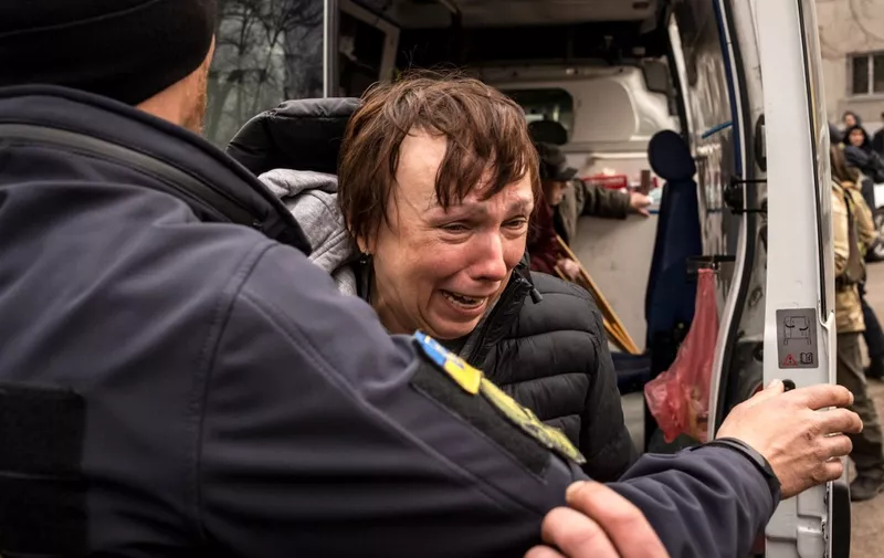 A woman is helped out of an ambulance after fleeing her home in the suburbs of Kyiv, on March 26, 2022, during Russia's military invasion launched on Ukraine. (Photo by FADEL SENNA / AFP)