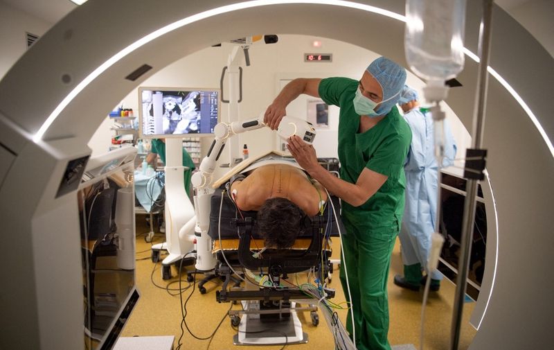 A surgeon prepares to install the Cirq robotic arm of the Loop-X robotic-assisted surgery installation to secure his work on the spine of a patient affected by a metastatic breast cancer, on June 10, 2021 at the University-affiliated hospital (CHU) in Angers, western France. - The Loop-X robotic-assisted surgery installation is a premiere in Europe. (Photo by LOIC VENANCE / AFP)