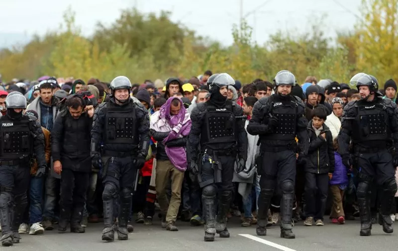 A group of about 1,000 migrants is escorted by Slovenian police officers from the border crossing with Croatia, on October 22, 2015, near the village Rigonce to Dobova in Slovenia. More than 12,600 migrants arrived in Slovenia over a 24-hour period, police said on October 22, 2015, a record that surpasses even that in Hungary at the height of the crisis in September. AFP PHOTO / STRINGER
