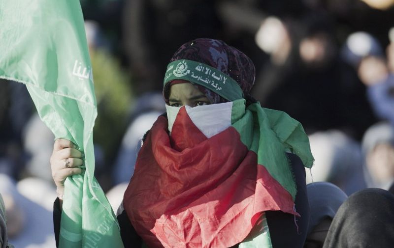 A Palestinian woman covering her face with her national flag takes part in an anti-Israel rally in Gaza City, on December 6, 2015. AFP PHOTO / SAID KHATIB / AFP / SAID KHATIB