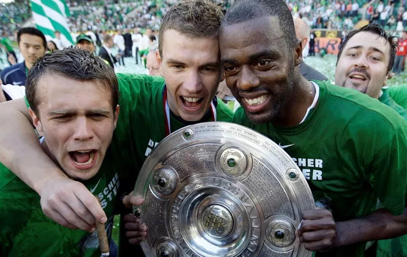 VfL Wolfsburg's Zvjedzan Misimovic, Edin Dzeko and Grafite (L-R) celebrate the German soccer championship with the trophy after their German Bundesliga soccer match against Werder Bremen in Wolfsburg May 23, 2009. REUTERS/Thomas Bohlen (GERMANY SPORT SOCCER) ONLINE CLIENTS MAY USE UP TO SIX IMAGES DURING EACH MATCH WITHOUT THE AUTHORITY OF THE DFL. NO MOBILE USE DURING THE MATCH AND FOR A FURTHER TWO HOURS AFTERWARDS IS PERMITTED WITHOUT THE AUTHORITY OF THE DFL. FOR MORE INFORMATION CONTACT DFL DIRECTLY