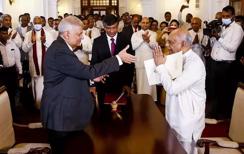 Sri Lakan President Ranil Wickremesinghe (L) gestures after swearing in Dinesh Gunawardena (R) as Sri Lanka's new Prime Minister, at the prime minister office in Colombo on July 22, 2022. (Photo by AFP)