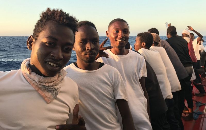 Rescued migrants stand on deck to watch the sunset aboard the 'Ocean Viking' rescue ship, operated by French NGOs SOS Mediterranee and Medecins sans Frontieres (MSF) on August 15, 2019, during a search-and-rescue operation in the Mediterranean Sea. - The Ocean Viking rescue ship, operated by SOS Mediterranee and Doctors without Borders (MSF), is looking for a port to dock with more than 350 migrants on board. (Photo by Anne CHAON / AFP)
