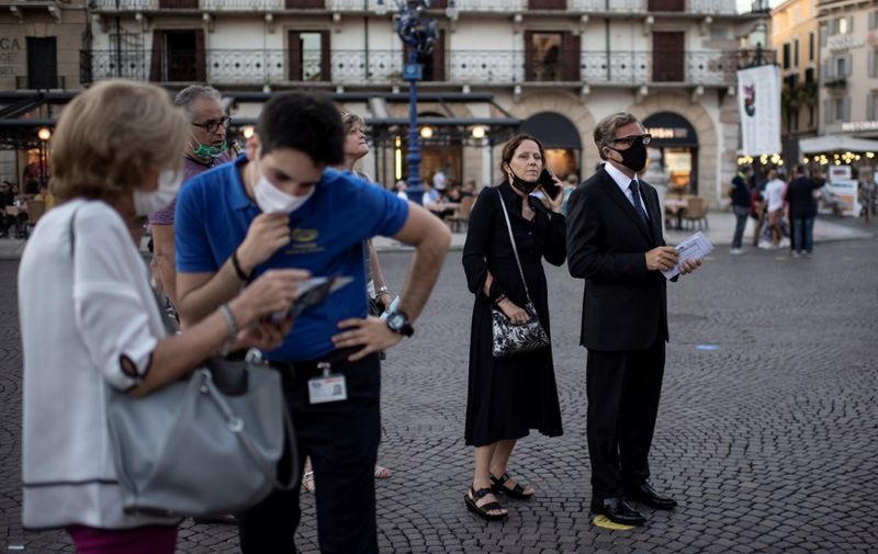 Guests wearing face masks wait as they arrive before a concert at the Arena in Verona, northern Italy, on July 25, 2020. - This is the first show with new dispositions against the spread of the novel coronavirus (Covid-19) during this season. (Photo by MARCO BERTORELLO / AFP)