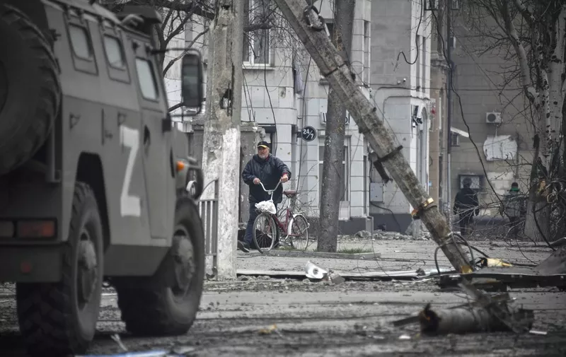 A man walks with a bicycle in central Mariupol on April 12, 2022, as Russian troops intensify a campaign to take the strategic port city, part of an anticipated massive onslaught across eastern Ukraine, while Russia's President makes a defiant case for the war on Russia's neighbour. - *EDITOR'S NOTE: This picture was taken during a trip organized by the Russian military.* (Photo by Alexander NEMENOV / AFP)
