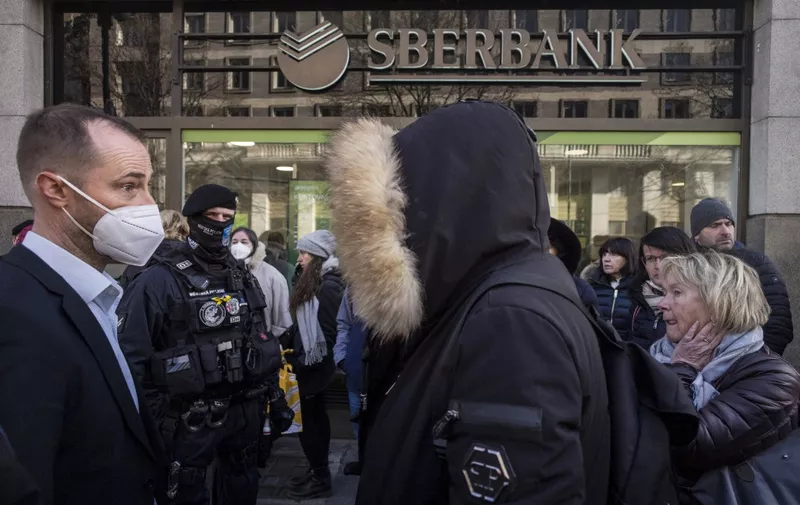 People queue outside a branch of Russian state-owned bank Sberbank to withdraw their savings and close their accounts in Prague on February 25, 2022, before Sberbank will close all its branches in the Czech Republic later in the day. - US President Biden was the first to announce sanctions, hours after Russian President Putin declared a "military operation" into Ukraine. The first tranche will hit four Russian banks -- including the country's two largest, Sberbank and VTB Bank -- cut off more than half of Russia's technology imports, and target several of the country's oligarchs. (Photo by Michal Cizek / AFP)