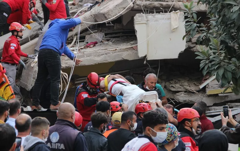Rescuers and local volunteers carry a wounded victim on a stretcher form a collapsed building after a powerful earthquake struck Turkey's western coast and parts of Greece, in Izmir, on October 30, 2020. - A powerful earthquake hit Turkey and Greece on October 30, killing at least six people, levelling buildings and creating a sea surge that flooded streets near the Turkish resort city of Izmir. (Photo by - / IHLAS NEWS AGENCY / AFP) / Turkey OUT