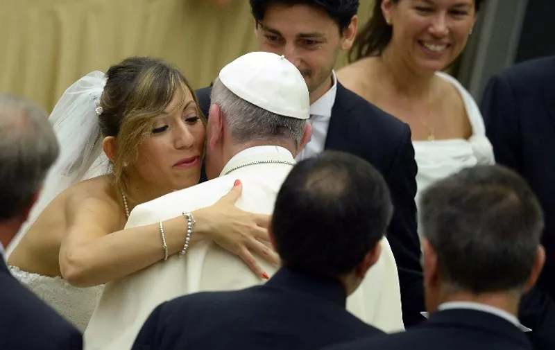 Pope Francis is greeted by newlyweds during a general audience at the Vatican's Paul VI hall on August 5, 2015. Divorced people who have remarried "are still part of the Church" and should not be treated as if they have been excommunicated or cast out, Pope Francis said today.   AFP PHOTO / FILIPPO MONTEFORTE