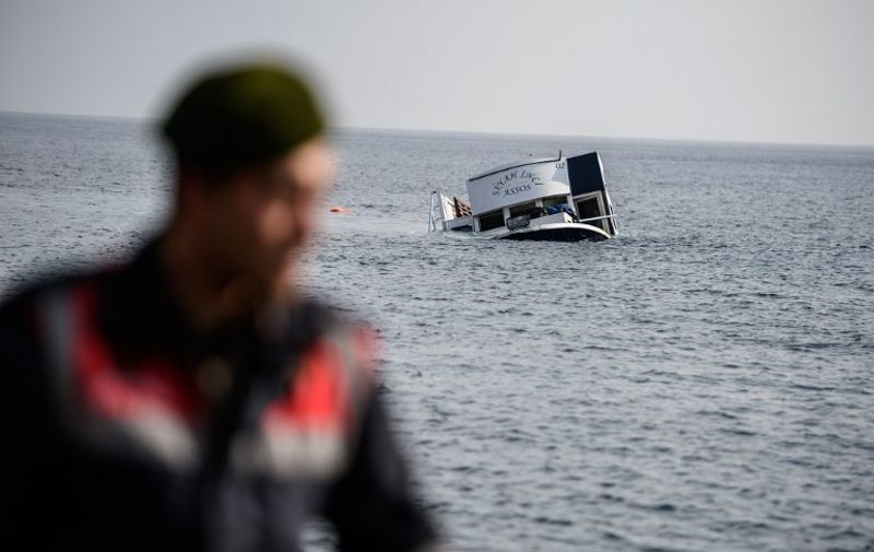 A sinking boat is seen behind a Turkish gendarme off the coast of Canakkale's Bademli district on January 30, 2016.
At least 33 migrants drowned on January 30 when their boat sank in the Aegean Sea while trying to cross from Turkey to Greece, Turkey's state-run Anatolia news agency reported. The migrants, who included those from Myanmar, Afghanistan and Syria, set sail from the Canakkale province to reach the nearby Greek island of Lesbos, Anatolia said. 
 / AFP / OZAN KOSE