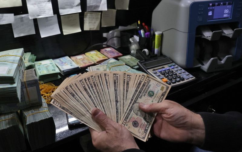 A man handles US dollars bills at a currency exchange office in Beirut on March 14, 2023. The Lebanese pound sank to a historic low against the dollar on the parallel market today, foreign  exchange dealers said, as banks in the crisis-hit country resumed an open-ended strike. (Photo by ANWAR AMRO / AFP)