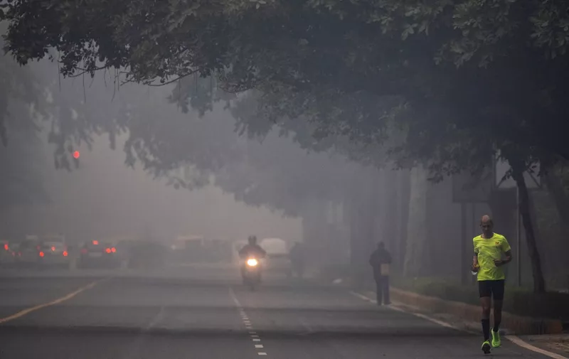 A man runs along a street amid smoggy conditions in New Delhi on December 2, 2021. (Photo by Jewel SAMAD / AFP)