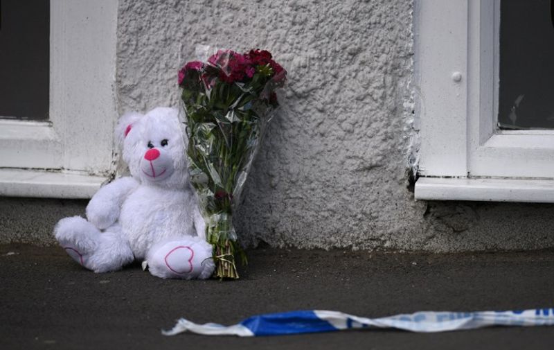 A floral tribute and a teddy bear are pictured alongside police tape near to the Manchester Arena, in Manchester, northwest England on May 23, 2017 following a deadly terror attack at the Ariana Grande concert at the Manchester Arena the night before. 
Twenty two people have been killed and dozens injured in Britain's deadliest terror attack in over a decade after a suspected suicide bomber targeted fans leaving a concert of US singer Ariana Grande in Manchester. / AFP PHOTO / Oli SCARFF