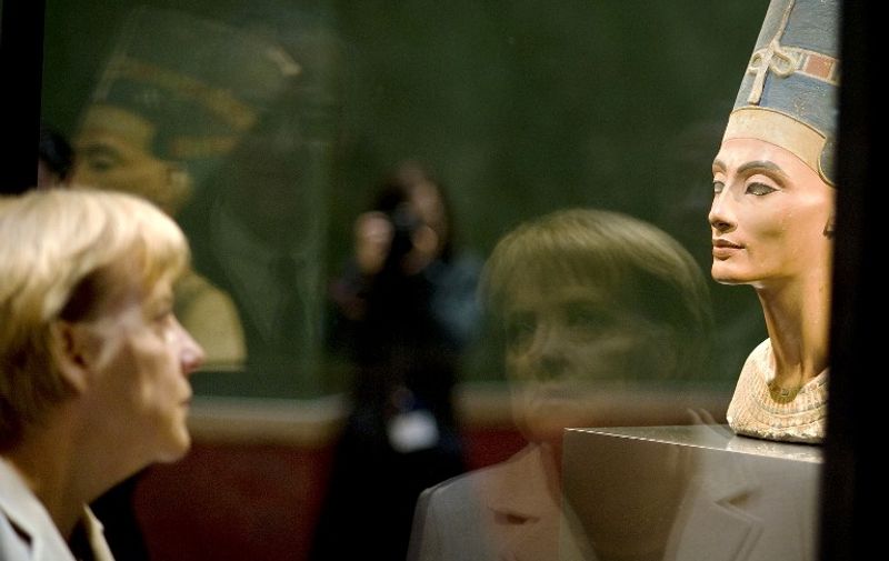 German Chancellor Angela Merkel looks at 3,400-year-old Egyptian beauty Queen Nefertiti as she visits Berlin's "Neues Museum" (New Museum) during the official opening on October 16, 2009. The Museum is to be re-opened to the public on October 17, 2009. After around ten years of planning, restoration and rebuilding lead by British architect David Chipperfield, the Neues Museum, heavily damaged and partly destroyed in the Second World War and still ruin at the time of German reunification, has been rebuilt and its remaining parts carefully restored. AFP PHOTO Bundesregierung / GUIDO BERGMANN