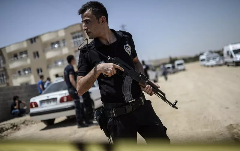 Turkish police stand near a building, where two police officers were found shot dead at their home on July 22, 2015 in the Turkish town of Ceylanpinar on the border with Syria. The military wing of the outlawed Kurdistan Workers' Party (PKK) said on July 22 it killed two Turkish police officers in a town on the Syrian border as a reprisal for a suicide bombing blamed on jihadists that killed 32. AFP PHOTO / BULENT KILIC / AFP / BULENT KILIC