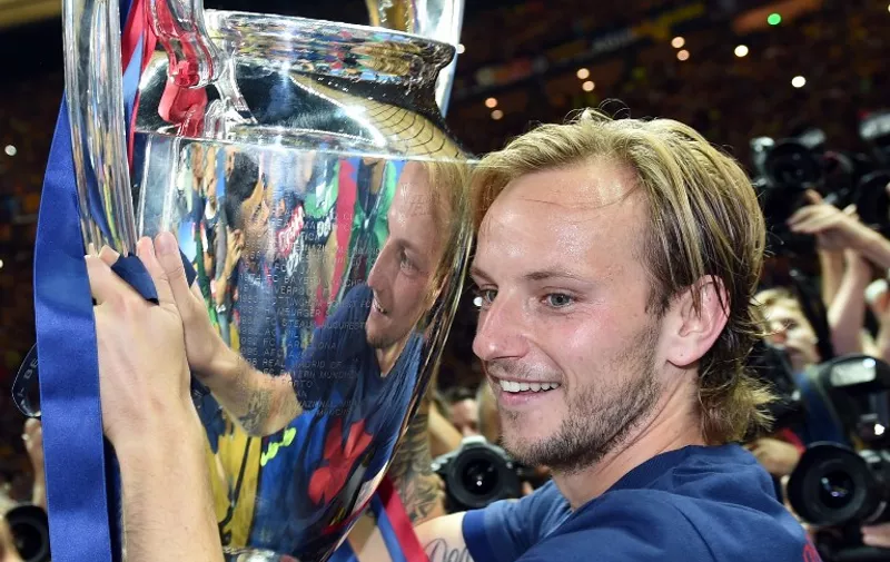 Barcelona's Croatian midfielder Ivan Rakitic holds the trophy after the UEFA Champions League Final football match between Juventus and FC Barcelona at the Olympic Stadium in Berlin on June 6, 2015. FC Barcelona won the match 1-3.        AFP PHOTO / PATRIK STOLLARZ