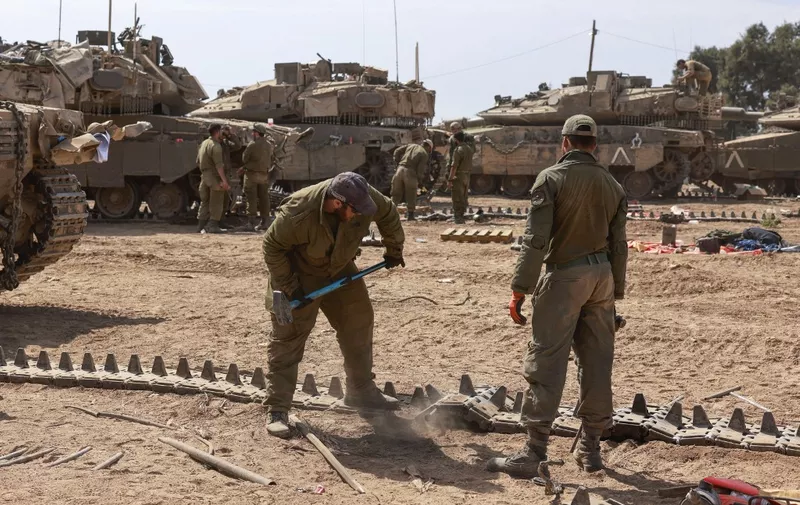 Israeli soldiers work on their tanks in a army camp near Israel's border with the Gaza Strip on April 8, 2024, amid the ongoing conflict between Israel and the militant group Hamas. (Photo by Menahem Kahana / AFP)