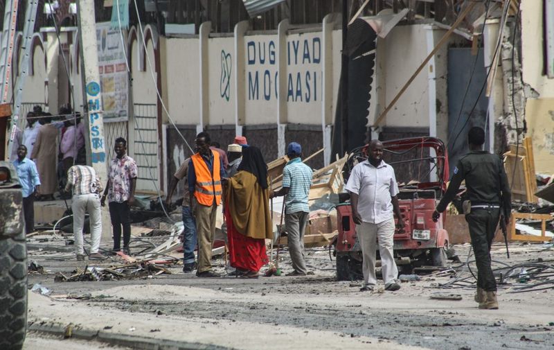 Police officers and people stand at the bomb explosion site in Mogadishu, Somalia, on November 25, 2021. - Five people were killed and over a dozen injured in a car bombing near a school in Somalia's capital Mogadishu on November 25, 2021, a security official said, in the latest attack to hit the troubled country. (Photo by AFP)