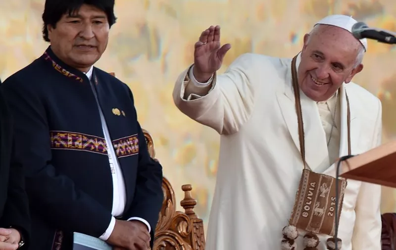 Pope Francis (R) waves next to Bolivian President Evo Morales during a ceremony in El Alto, upon landing in the country on July 8, 2015. Pope Francis, the first Latin American pontiff, arrived in Bolivia on the second leg of a three-nation tour of the continent's poorest countries, where he has been acclaimed by huge crowds.  AFP PHOTO / CRIS BOURONCLE