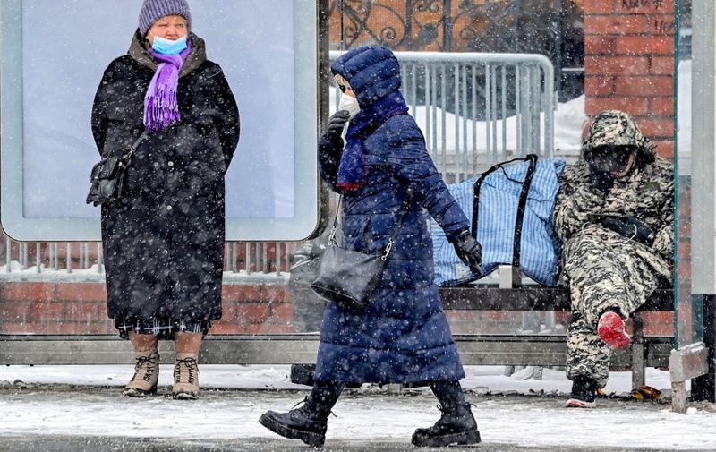 A woman wearing a protective facemask walks in the streets of central Moscow as it snows, on February 22, 2021, while the country faces a new wave of Covid-19 infections. (Photo by Yuri KADOBNOV / AFP)