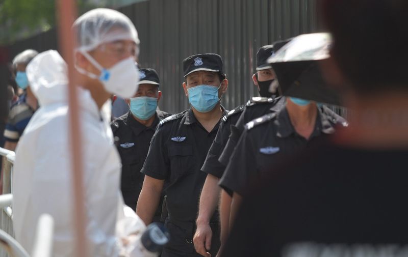 Security guards wait in line to undergo COVID-19 coronavirus swab tests at a testing station in Beijing on June 30, 2020. - China's capital has partially lifted a weeks-long lockdown imposed to head off a feared second wave of coronavirus infections after more than eight million samples have been taken. (Photo by GREG BAKER / AFP)