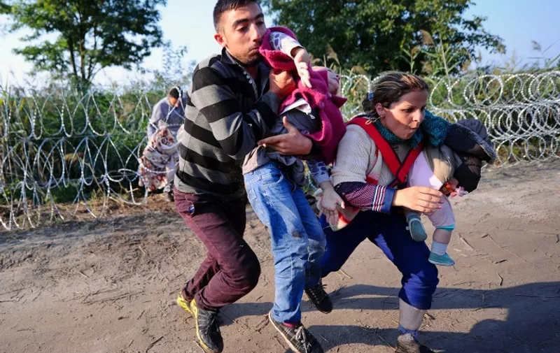 Migrants run after crawling under a barbed fence at the Hungarian-Serbian border near Roszke, on August 27, 2015. As Europe struggles with its worst migrant crisis since World War II, Hungary has become, like Italy and Greece, a "frontline" state. So far this year, police say around 141,500 migrants have been intercepted crossing into Hungary, mostly from neighbouring Serbia. AFP PHOTO / ATTILA KISBENEDEK