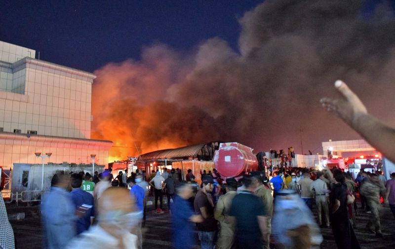 People gather as a massive fire engulfs the coronavirus isolation ward of Al-Hussein hospital in the southern Iraqi city of Nasiriyah, late on July 12, 2021. (Photo by Asaad NIAZI / AFP)
