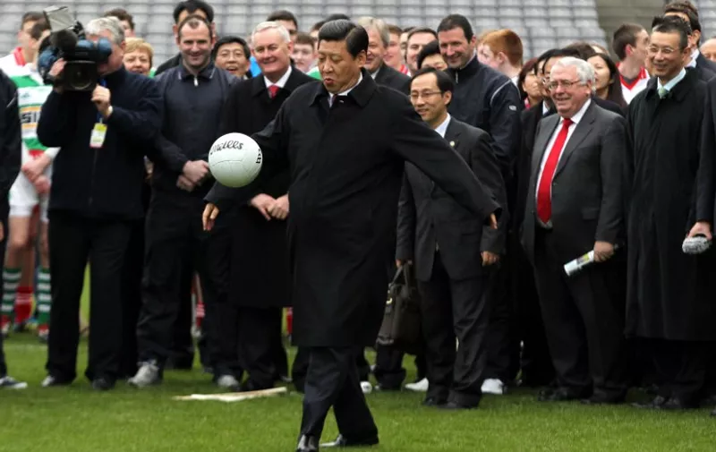 Chinese Vice-President Xi Jinping (C) kicks a Gaelic football as he visits the Croke Park in Dublin on February 19, 2012 to attend an exhibition of Gaelic football and hurling. Xi Jinping, China's leader-in-waiting, arrived on February 18 for a three-day visit to Ireland, nine years after he first visited the country. Xi will hold talks with Prime Minister Enda Kenny and attend an Ireland-China trade forum in Dublin involving about 300 companies. AFP PHOTO/ PETER MUHLY / AFP PHOTO / PETER MUHLY