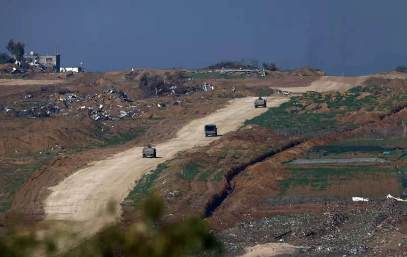This picture taken on January 14, 2024 from the Israeli border with the Gaza Strip shows Israeli army vehicles driving in the Gaza Strip, amid the ongoing battles between Israel and the militant Hamas group. (Photo by Menahem KAHANA / AFP)