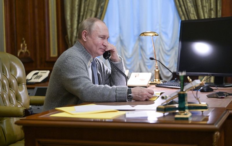 Russia's President Vladimir Putin speaks on the phone with participants of "The Christmas Tree Wishes" campaign in Strelna, outside St. Petersburg, on December 27, 2021. - The goal of the campaign is to make the New Year's dreams of orphans, children from low-income families, and disabled kids come true. (Photo by Alexey NIKOLSKY / SPUTNIK / AFP)