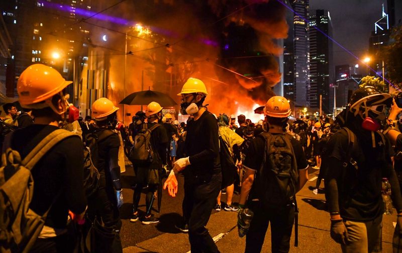 Protesters stand before a barricade they set on fire in the Wan Chai district in Hong Kong on August 31, 2019. - Chaos engulfed Hong Kong's financial heart on August 31 as police fired tear gas and water cannon at petrol bomb-throwing protesters, who defied a ban on rallying -- and mounting threats from China -- to take to the streets for a 13th straight weekend. (Photo by Lillian SUWANRUMPHA / AFP)