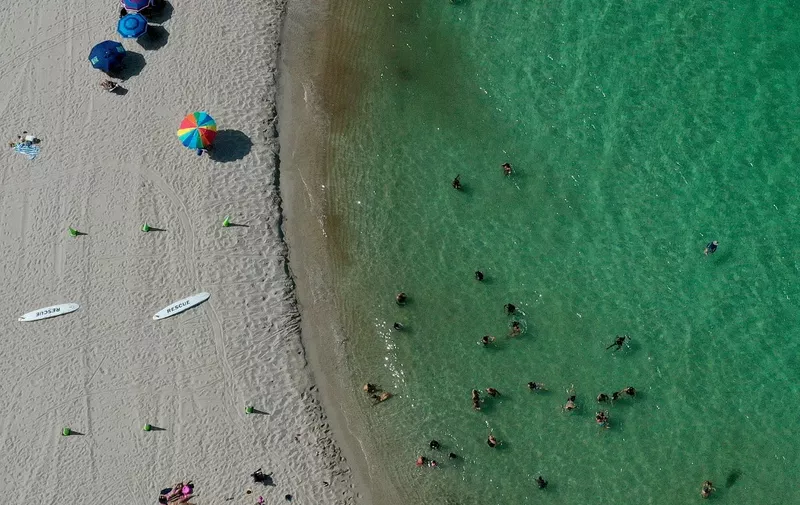 MIAMI, FLORIDA - JULY 11: In an aerial view, people enjoy the Atlantic Ocean's waters along the beach at Haulover Park on July 11, 2023 in Miami, Florida. The surface ocean temperatures in parts of Florida are 92 to 96 degrees Fahrenheit, the warmer coastal ocean water is threatening Florida's coral reefs, and could create stronger tropical storms and hurricanes.   Joe Raedle/Getty Images/AFP (Photo by JOE RAEDLE / GETTY IMAGES NORTH AMERICA / Getty Images via AFP)