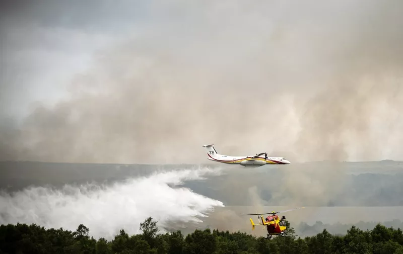 A De Havilland Canada Dash 8-400 MR aircraft drops water over a wildfire raging in the Monts d'Arree, near Brennilis, Brittany, on July 20, 2022. - A heatwave fuelling ferocious wildfires in Europe pushed temperatures in Britain over 40 degrees Celsius (104 degrees Fahrenheit) for the first time after regional heat records tumbled in France. (Photo by LOIC VENANCE / AFP)