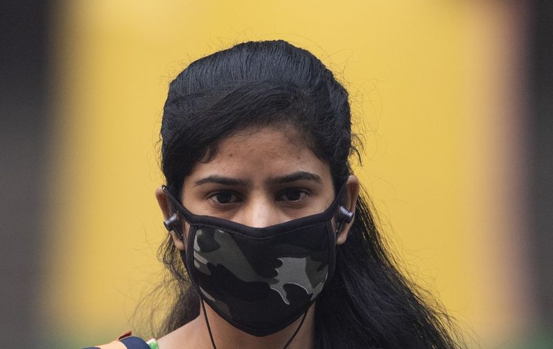 A woman wearing a protective face mask walks along a street in smoggy conditions in New Delhi on November 4, 2019. - Millions of people in India's capital started the week on November 4 choking through "eye-burning" smog, with schools closed, cars taken off the road and construction halted. (Photo by Jewel SAMAD / AFP)