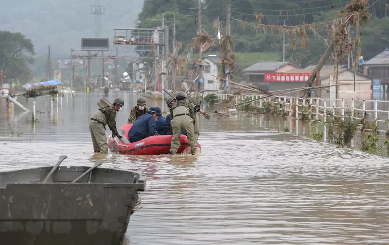 Japan Self-Defense Forces and police officers handle an inflatable boat to join rescue operations at a nursing home following heavy rain in Kuma village, Kumamoto prefecture, on July 5, 2020. - Two people died and 16 others were feared dead, local media said after torrential rain in western Japan triggered massive floods and mudslides. (Photo by STR / JIJI PRESS / AFP) / Japan OUT
