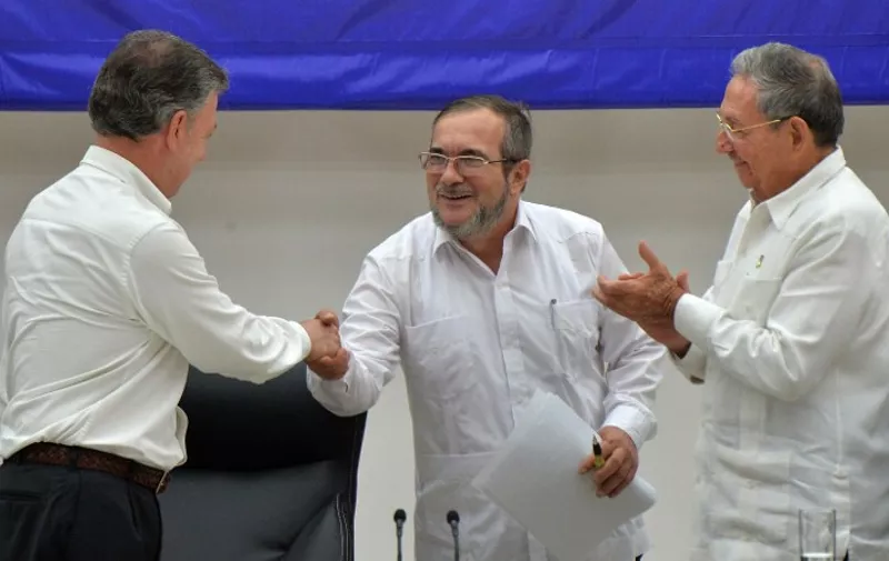 Colombian President Juan Manuel Santos (L), the head of Colombia's FARC guerilla, Timoleon Jimenez, aka "Timochenko" (C) and Cuban President Raul Castro (R), during the  signing of the ceasefire between the Colombian government and the FARC guerrilla in Havana on June 23, 2016.
Colombia's government and the FARC guerrilla force signed a definitive ceasefire Thursday, taking one of the last crucial steps toward ending Latin America's longest civil war. / AFP PHOTO / ADALBERTO ROQUE
