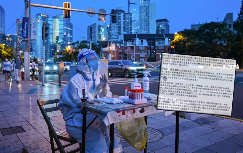 (FILES) In this file photo taken on July 5, 2022, a health worker waits to test people for the Covid-19 coronavirus on a street next to a residential area in the Jing'an district of Shanghai. - China's economy grew 3.9 percent year-on-year in the third quarter, according to official data released on October 24, 2022, beating forecasts a day after a major political meeting re-elected President Xi Jinping for another five years in office. (Photo by Hector RETAMAL / AFP)